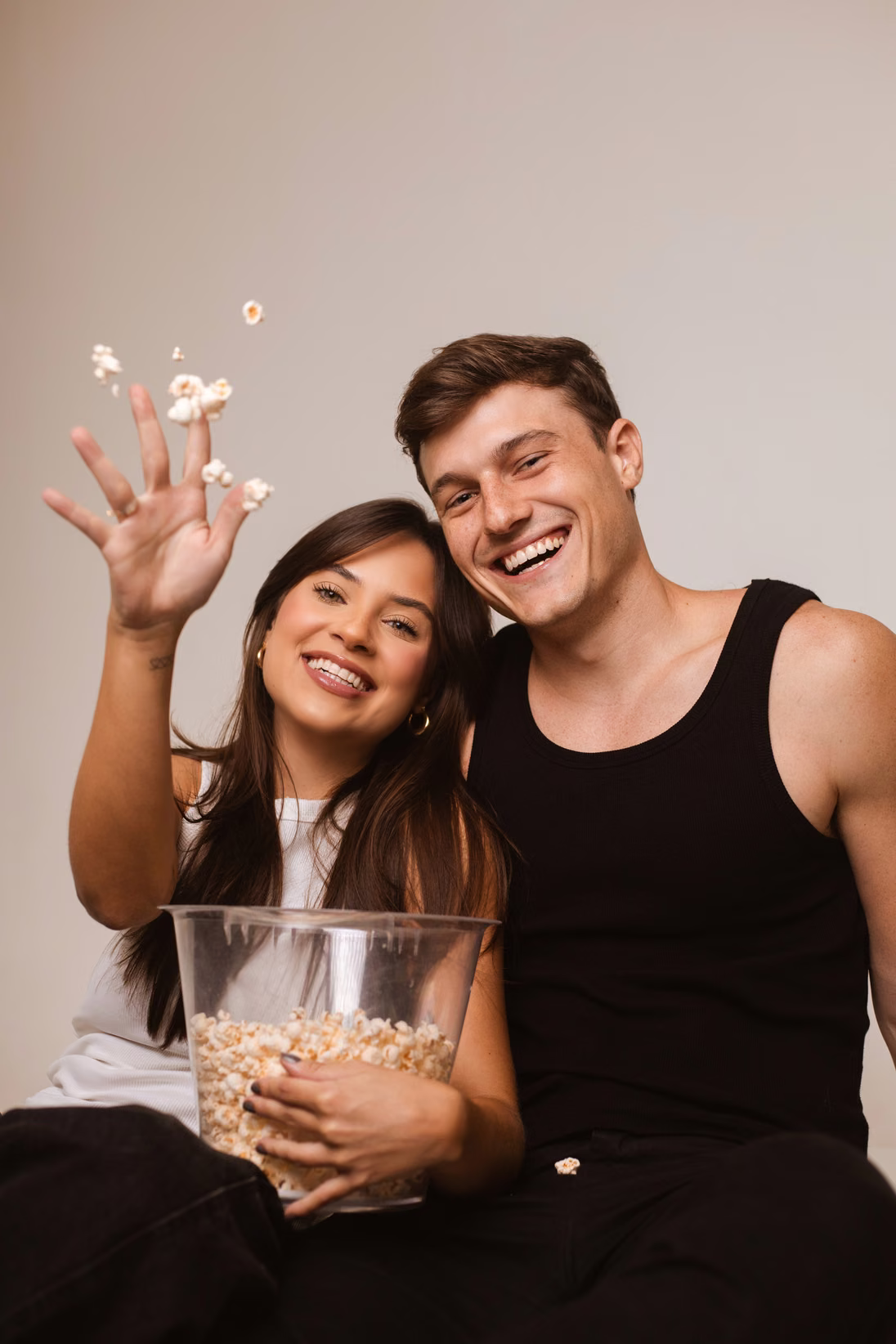Clara Diniz e João Vitor rindo com um pote de pipoca